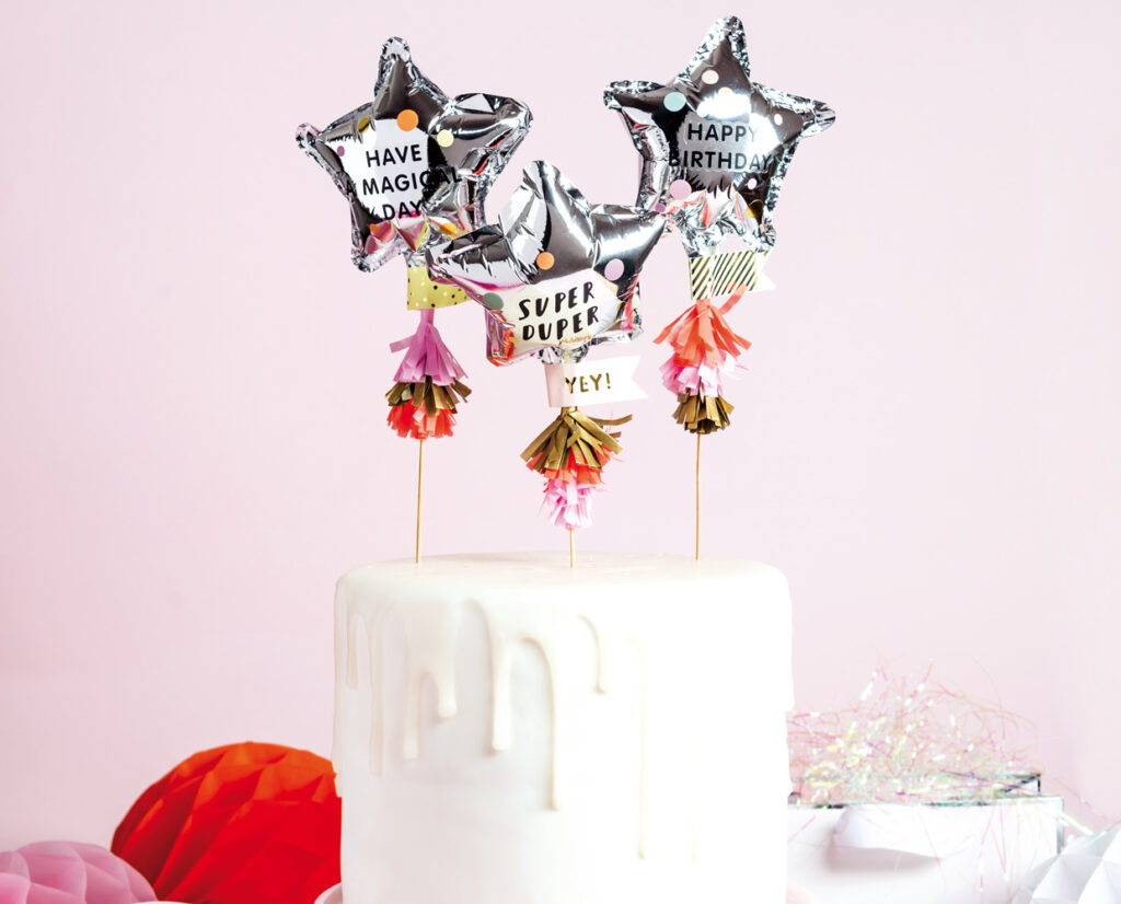 Kuchentopper gestalten mit Folienballons in Sternenform, MIni-Tasseln aus Seidenpapier und fertig drapiert im Kuchen