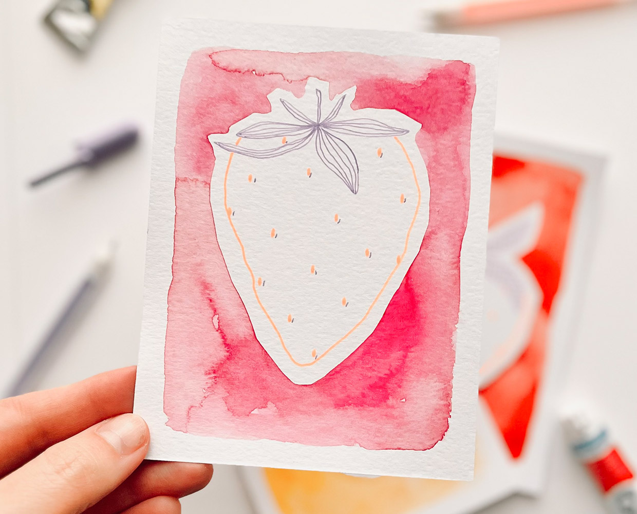 Mixed Media: Erdbeere aus Gelstiften auf aquarelliertem, roten Hintergrund