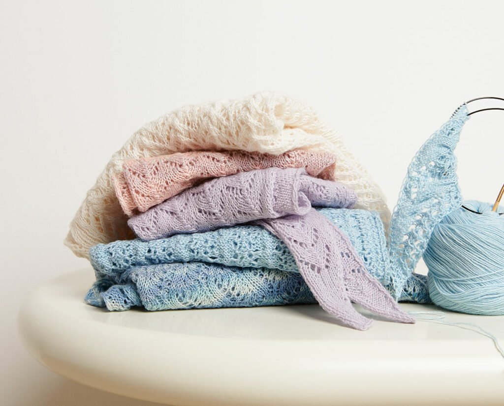 Stapel mit sommerlichen Strickstücken aus Sommergarnen
